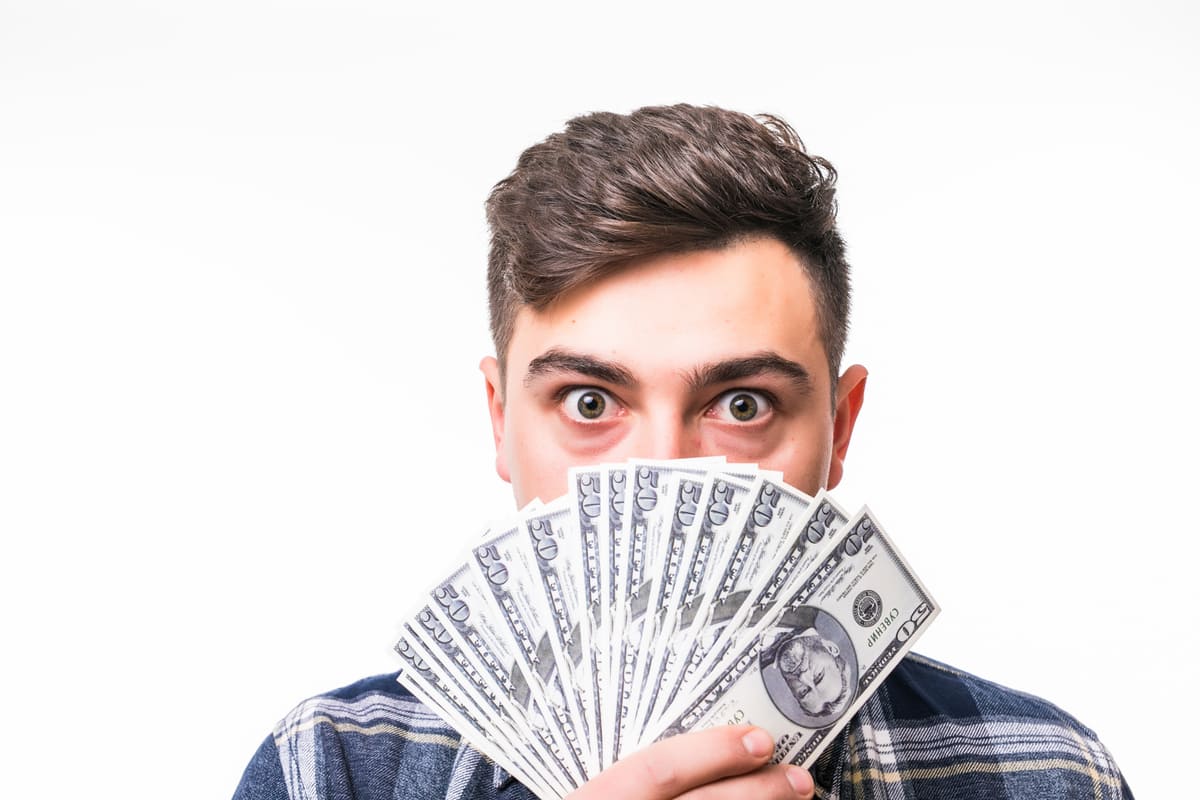 Face of young rich man covered with fan of money