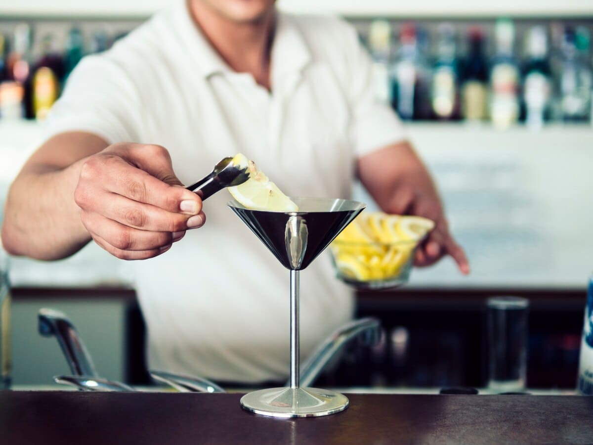 Male bartender serving cocktail in stainless martini glass