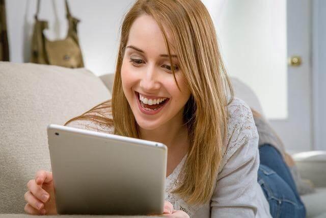 Woman on couch using tablet, potentially